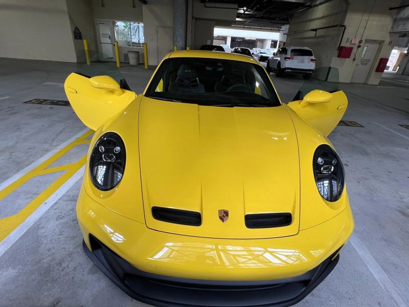 Yellow Porsche 911 GT3 with both doors open in a parking garage