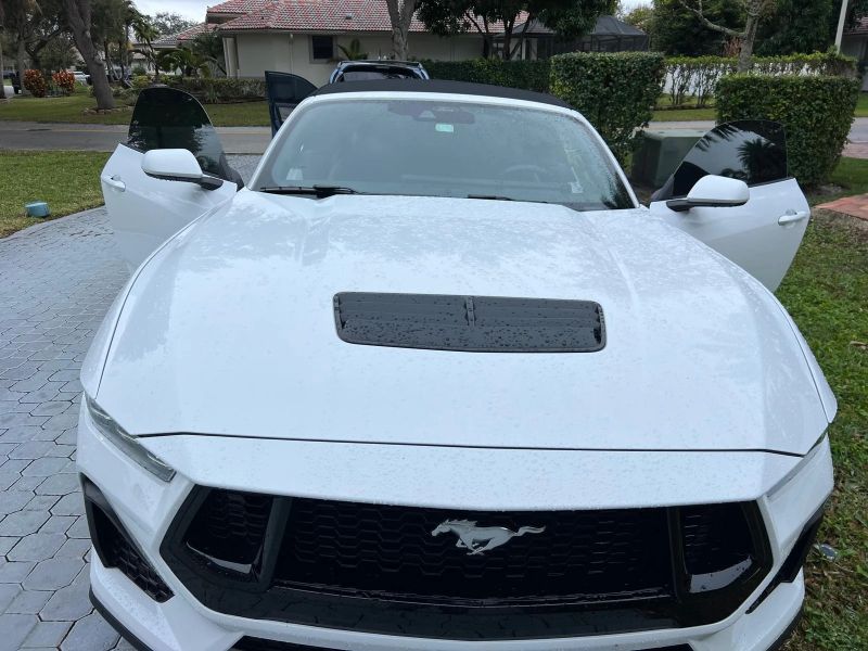 White Ford Mustang convertible from the front with both doors open and tinted windows